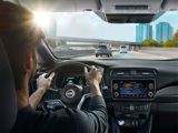 Woman driving a Nissan LEAF from the inside of the vehicle showing the dashboard 